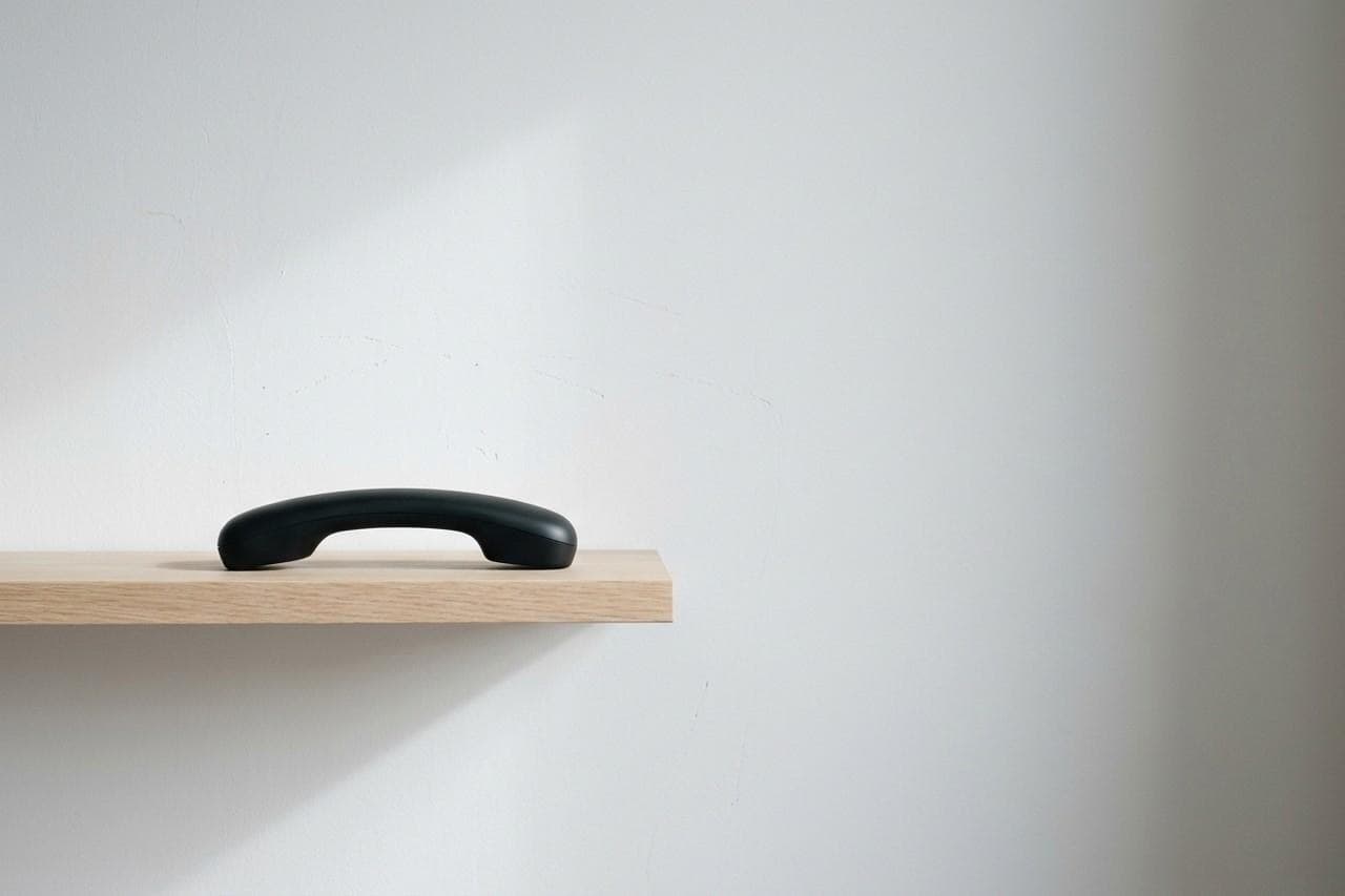 Telephone handset on a pale shelf against a white wall